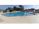 A community pool offers a place to relax with chairs and umbrellas, surrounded by a white metal fence at 8609 Regal Ln, Hudson, FL 34667