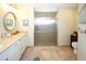 Bright bathroom features a neutral countertop, white cabinets, a glass enclosed shower, and tiled floors at 8609 Regal Ln, Hudson, FL 34667