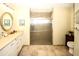Bright bathroom features a neutral countertop, white cabinets, a glass enclosed shower, and tiled floors at 8609 Regal Ln, Hudson, FL 34667