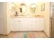 Bright bathroom features dual sinks, white cabinets, neutral countertops, tiled floor, and decorative accents at 8609 Regal Ln, Hudson, FL 34667