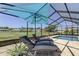 Screened in pool area with lounge chairs overlooking a golf course at 8609 Regal Ln, Hudson, FL 34667