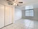 Bright bedroom features tiled floors, a ceiling fan, and a large closet for ample storage space at 9402 Barrington Ln, Port Richey, FL 34668