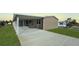 Tan home exterior with a covered carport, grassy lawn, and a concrete driveway at 9896 Scepter Ave, Brooksville, FL 34613