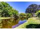 Picturesque view of a pond reflecting the surrounding greenery and blue sky at 9925 Whitworth Ct, New Port Richey, FL 34655