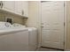 Functional laundry room with washer, dryer, white cabinets and an exterior door at 10056 Lebanon Dr, Port Charlotte, FL 33981