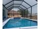 Screened-in pool with blue tile accents, lounge chair, and clear water at 10056 Lebanon Dr, Port Charlotte, FL 33981