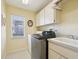 Laundry room featuring white cabinets, tile flooring and front loading washer and dryer at 10285 Velvetseed Cir, Spring Hill, FL 34608