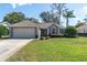 Single-story home with attached garage, manicured lawn, and inviting curb appeal at 10308 Pineneedles Dr, New Port Richey, FL 34654