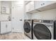 Well-organized laundry room with white cabinetry, a sink, and stainless steel washer and dryer at 12215 Snead Pl, Tampa, FL 33624