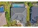 Aerial view of house with a screened pool, landscaped yard, and a dark shingle roof at 12446 Quail Ridge Dr, Spring Hill, FL 34610