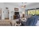 Comfortable living room with ceiling fan, tile floors, and view of screened patio and outdoor greenery at 12446 Quail Ridge Dr, Spring Hill, FL 34610
