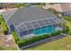 Aerial view of a screened pool and lanai, surrounded by green grass and landscaping at 12446 Quail Ridge Dr, Spring Hill, FL 34610