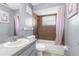 Well-lit bathroom featuring a shower-tub combo, vanity and pink shower curtains at 1283 Coble Rd, Spring Hill, FL 34608