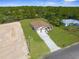 Aerial view of a house with a spacious driveway and lawn, close to power lines and a construction site at 16043 Penn State Rd, Weeki Wachee, FL 34614