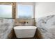 Elegant bathroom with a standalone tub, marble tile, and modern fixtures beneath a bright window at 16043 Penn State Rd, Weeki Wachee, FL 34614