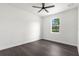 Empty bedroom featuring dark wood-look floors, bright white walls, and a sunny window highlighting the simple decor at 16043 Penn State Rd, Weeki Wachee, FL 34614