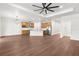 Spacious living area with a large fan, wood-look flooring, and an open view to the modern kitchen at 16043 Penn State Rd, Weeki Wachee, FL 34614