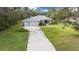 Aerial view showcasing the home's long driveway and lush landscaping, set on a spacious lot at 16386 Heron Hills Dr, Spring Hill, FL 34610