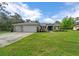 Well-maintained single-story home with a lush front lawn and a three-car garage, offering curb appeal at 16386 Heron Hills Dr, Spring Hill, FL 34610