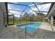 Inviting screened-in pool area featuring a refreshing pool and brick patio, perfect for outdoor relaxation at 16386 Heron Hills Dr, Spring Hill, FL 34610