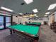 Recreational billiard room featuring multiple pool tables, pendant lighting, and comfortable seating at 18045 Tarrington Pl, Hudson, FL 34667
