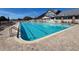 Community pool with surrounding lounge chairs and view of the clubhouse at 18045 Tarrington Pl, Hudson, FL 34667