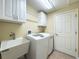 Functional laundry room includes a sink, washer and dryer, storage cabinets, and tiled flooring at 18045 Tarrington Pl, Hudson, FL 34667