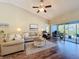 Bright living room with a vaulted ceiling, ceiling fan, wood floors, and sliding glass doors at 18045 Tarrington Pl, Hudson, FL 34667