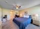 Well-lit main bedroom featuring a ceiling fan, carpeted floors, and an ensuite bathroom at 18045 Tarrington Pl, Hudson, FL 34667
