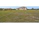 Tan home with large grassy area and neutral trim and roofing details at 18317 Treehaven Dr, Hudson, FL 34667