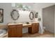 Well-lit bathroom featuring dual sinks, decorative mirrors, and a separate toilet room at 19263 Quiet Oak Ln, Brooksville, FL 34604