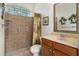 Bathroom with tiled shower, glass-block window, and vanity with a framed mirror at 19263 Quiet Oak Ln, Brooksville, FL 34604