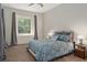 Comfortable carpeted bedroom featuring a ceiling fan and large window with wooded view at 19263 Quiet Oak Ln, Brooksville, FL 34604