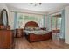 Bright bedroom with wood floors, a large window and a decorative dresser creating a relaxing retreat at 19263 Quiet Oak Ln, Brooksville, FL 34604