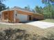 Side view of the home featuring an attached two-car garage with an expansive driveway and walkway at 19263 Quiet Oak Ln, Brooksville, FL 34604