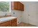 Functional laundry room with cabinets, sink, and a view of a tree from a window at 19263 Quiet Oak Ln, Brooksville, FL 34604