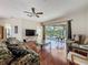 Spacious living room with hardwood floors, ceiling fan, sliding glass doors, and a view of the backyard at 3555 Sylvan Edge Dr, Palm Harbor, FL 34685