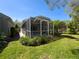 A spacious screened porch offers a relaxing outdoor living space with verdant landscaping and ample seating area at 3555 Sylvan Edge Dr, Palm Harbor, FL 34685