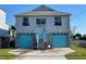 Charming two-story home with vibrant blue garage doors and elevated design for waterfront living at 4046 Casa Ct, Hernando Beach, FL 34607