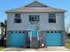 Charming raised home featuring two-story design, blue garage doors, and welcoming front entrance at 4046 Casa Ct, Hernando Beach, FL 34607