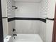 A remodeled bathroom with black and white tiled walls, a white tub, and dark fixtures at 4601 N 37Th St, Tampa, FL 33610