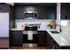 A modern kitchen with dark cabinets, stainless steel appliances, and a light countertop at 4601 N 37Th St, Tampa, FL 33610
