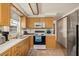 Well-lit kitchen with wood cabinets, stainless steel refrigerator, and tile flooring; efficient design at 4743 Foothill Dr, Holiday, FL 34690