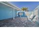 Inviting outdoor patio with white chairs, decorative block wall, pavers, and view of palm trees at 4924 Dory Dr, New Port Richey, FL 34652