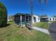 Charming single-story home featuring a screened-in porch, well-maintained lawn, and mature palm trees at 5211 Wisteria Cir, New Port Richey, FL 34653