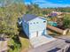 Exterior elevation view of home with blue siding, a two-car garage, and lush surroundings under blue skies at 6526 1St S Ave, St Petersburg, FL 33707