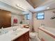 Well-lit bathroom with a vanity sink, decorative wallpaper, and a corner bathtub for relaxation at 7215 121St Ter, Largo, FL 33773