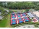 Aerial view of community pickleball courts featuring vibrant blue and red surfaces and well-maintained surrounding landscape at 7305 Sugarbush, Spring Hill, FL 34606