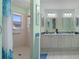Bright bathroom features a tiled shower and double vanity with mirrors and decorative backsplash at 7305 Sugarbush, Spring Hill, FL 34606