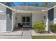 Inviting front porch with decorative accents, including a chair, lush greenery, and patterned concrete pathway at 7305 Sugarbush, Spring Hill, FL 34606